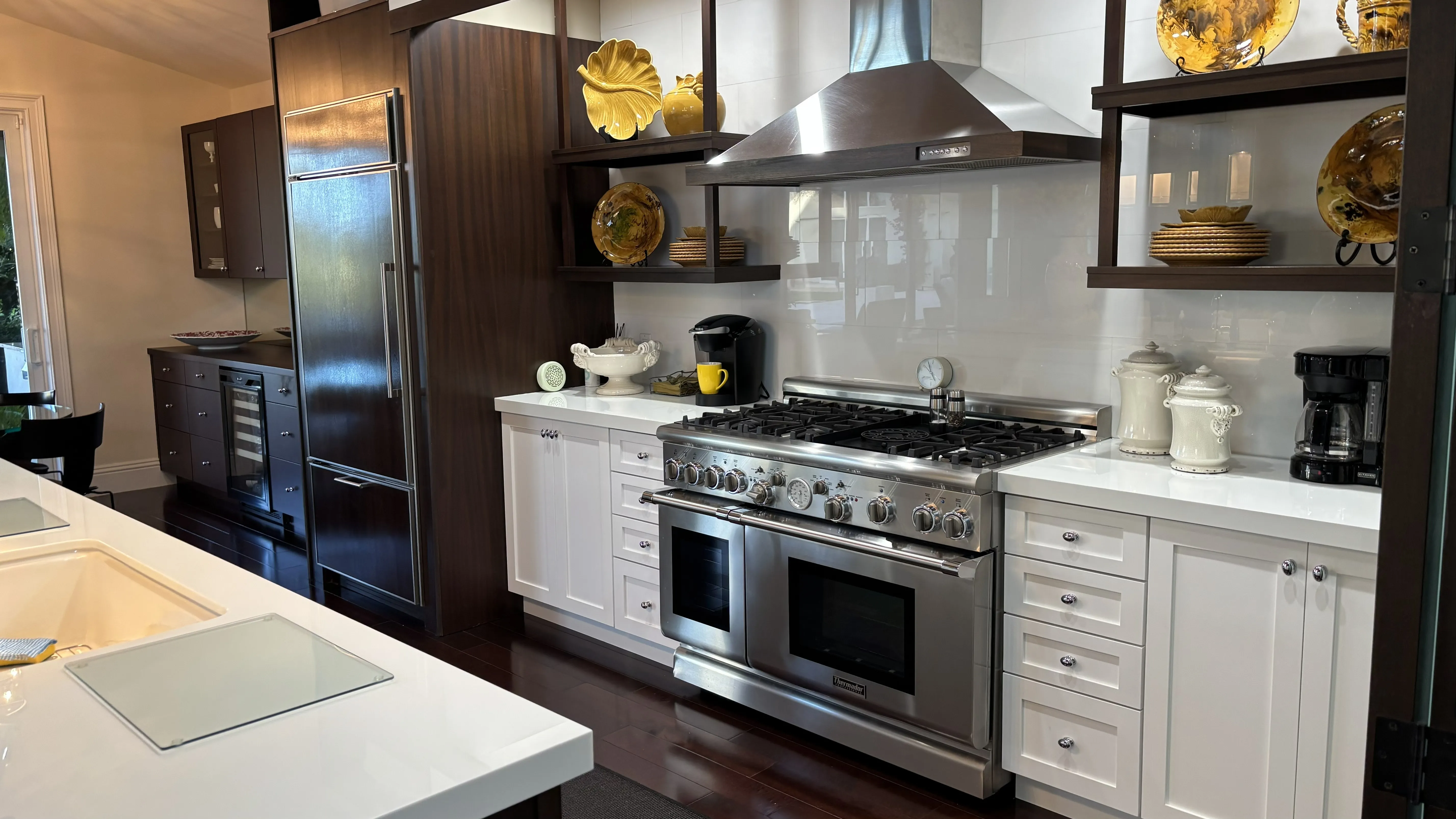 Modern kitchen featuring stainless steel appliances, white cabinetry, and decorative yellow dishes.