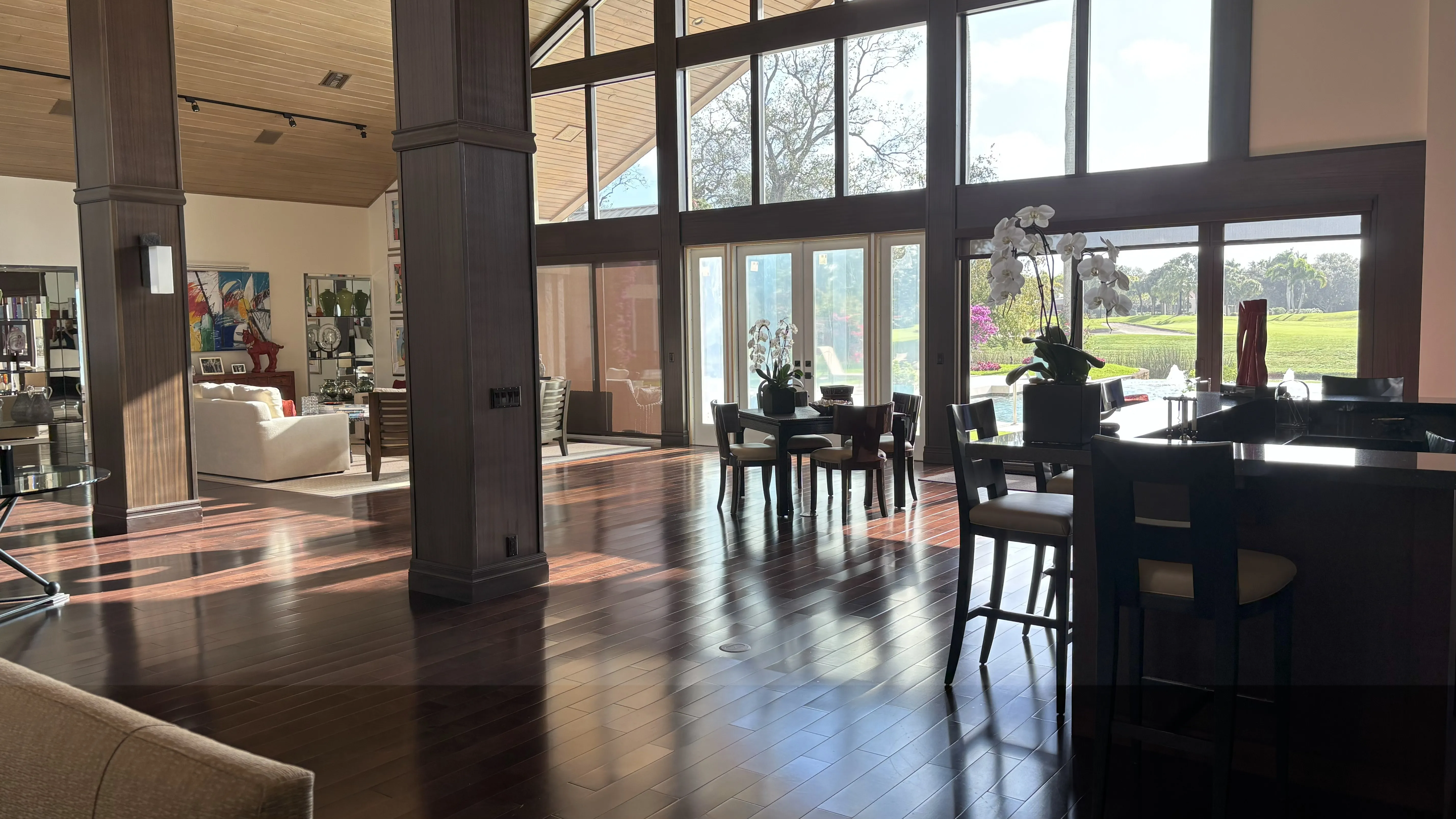 Modern living room with large windows, wooden floors, and elegant furnishings.
